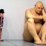 Scultura iperrealistica di uomo seduto in un angolo