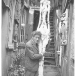 Annette-Giacometti-Alberto-Giacometti-nel-cortile-dell-atelier-con-il-gesso-della-Grande-donna-IV-1960-Archivi-della-Fondation-Giacometti-Parigi